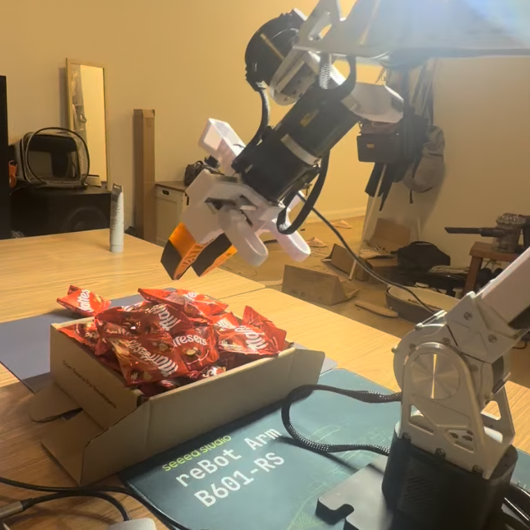 Clove arm positioned over a box of fragile packages, ready for policy inference